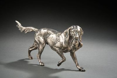 statue en argent représentant un chien en train de courir sur une surface grise