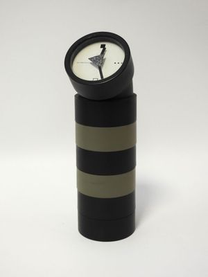 a black and white clock sitting on top of a black cylinder