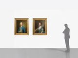 man standing in front of two paintings of men in a museum