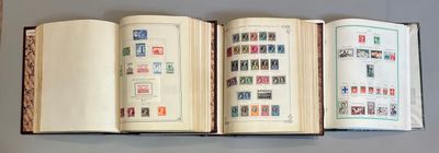 trois livres ouverts, sur lesquels sont apposés des timbres, posés sur une table