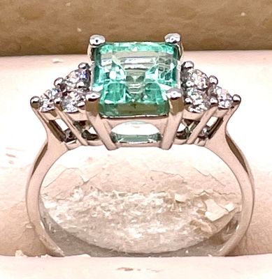 une image d'une bague avec une pierre verte entourée de diamants