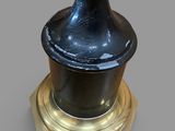 a black vase on a gold pedestal on a gray background