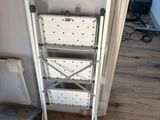 a white folding chair next to a shelf in a room