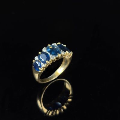 une bague en or sertie de saphirs bleus et de diamants sur un fond noir