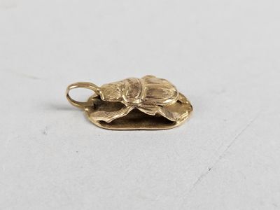 a gold plated turtle charm on a white surface