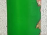 a green vase with a flower in it on a table