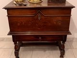 a small wooden chest with a clock on top of it