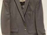 gray suit jacket hanging on a hanger on a white wall