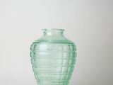 a green glass vase sitting on a white surface