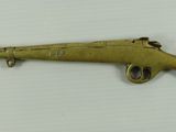 an old brass rifle with a wooden handle on a white surface