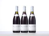 three bottles of wine are lined up on a white surface