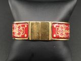 un gros plan d'un bracelet rouge et doré sur un mannequin