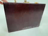 someone is holding a brown leather purse with a gold handle