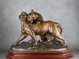 une statue en bronze représentant un lion et une lionne, posée sur un socle en bois