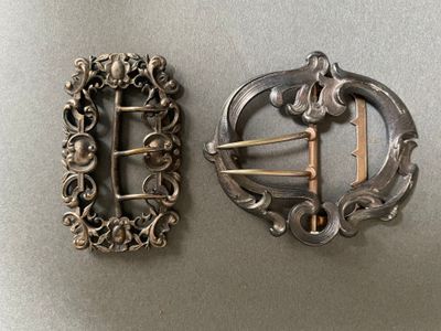 deux boucles anciennes en argent posées côte à côte sur une table