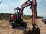 une pelleteuse rouge qui est à l'arrêt dans la terre