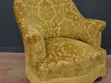une chaise jaune ornée de franges, posée devant un mur gris