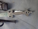a knife that is laying on the ground next to a glove