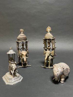 three silver figurines of elephants, a man, and a woman