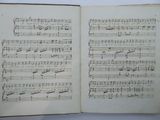 an open book with music notes on it sitting on a table