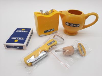 une tasse jaune, une théière, un paquet de cigarettes et une boîte de biscuits