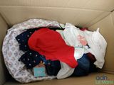 a cardboard box with a baby in it and clothes inside of it