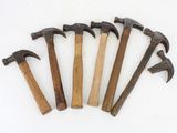 six old hammers are lined up on a white surface