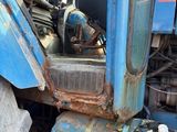 a blue tractor that is parked in the dirt