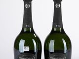 deux bouteilles de champagne posées l'une à côté de l'autre sur une surface blanche