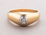 gros plan d'une bague en or avec un diamant au centre