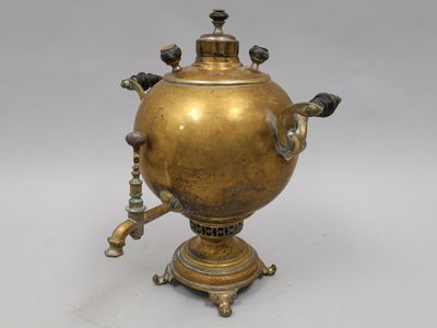 une théière ancienne en laiton posée sur un support et dotée d'un bec verseur