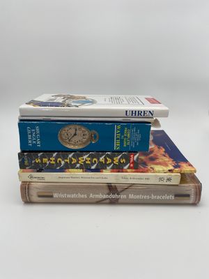 trois livres empilés sur une surface blanche