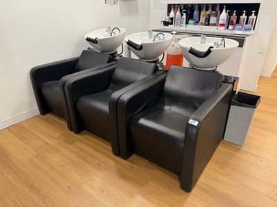 trois chaises noires dans une pièce équipée d'un lavabo et d'un miroir