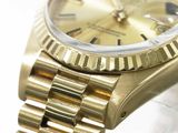 a gold watch that is sitting on a white surface