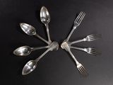 several spoons and forks arranged in a circle on a black surface
