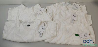 quatre t-shirts blancs posés sur une table, avec leurs étiquettes encore attachées