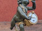 a statue of a boy playing a flute and holding a clock