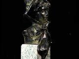 bronze bust of a young boy wearing a hat and a bow