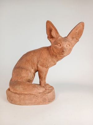 sculpture représentant un chat assis sur un rocher, posée sur une surface blanche