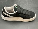 black and white puma sued sneakers on a gray surface