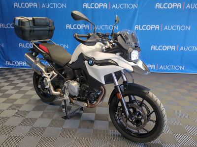 une moto blanche garée devant un fond bleu