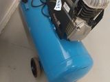 a blue air compressor sitting on the floor next to a wall