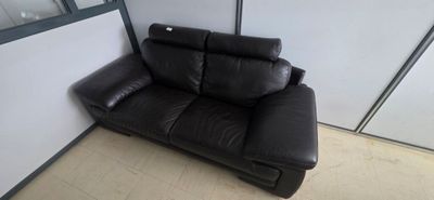 a black leather couch sitting in a corner of a room