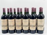 six bouteilles de vin sont alignées sur une surface blanche
