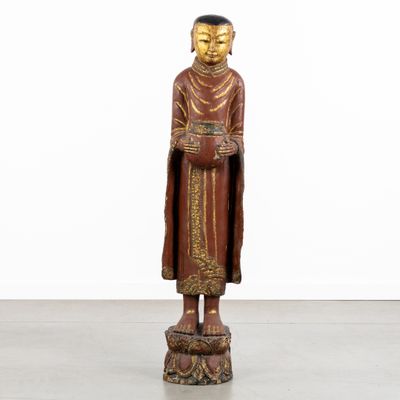 une statue en bois représentant un Bouddha debout sur un socle
