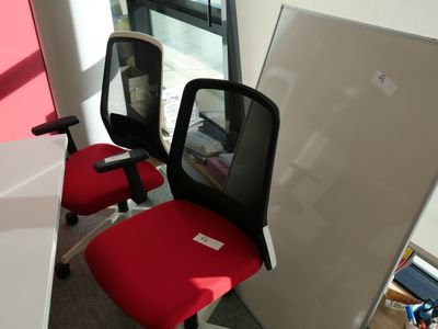 une chaise de bureau rouge et un bureau blanc dans une pièce