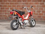 a small red motorcycle parked in front of a brick wall