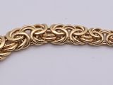 a close up of a gold chain bracelet on a white surface