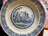 a blue and white plate sitting on a table next to a cell phone