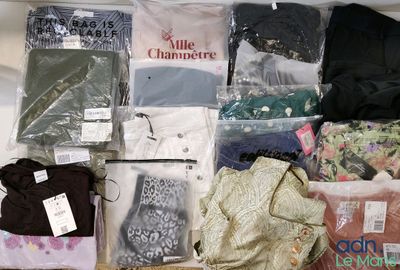 de nombreux vêtements de toutes sortes dans le sac posé sur le lit